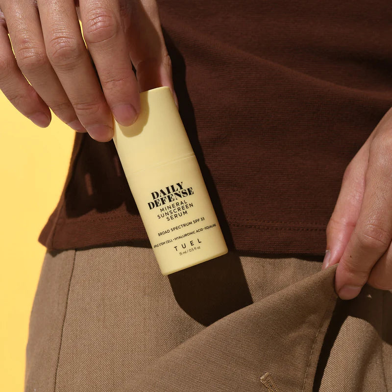 A small bottle of mineral sunscreen serum from Tuel skincare being put into a pant pocket.