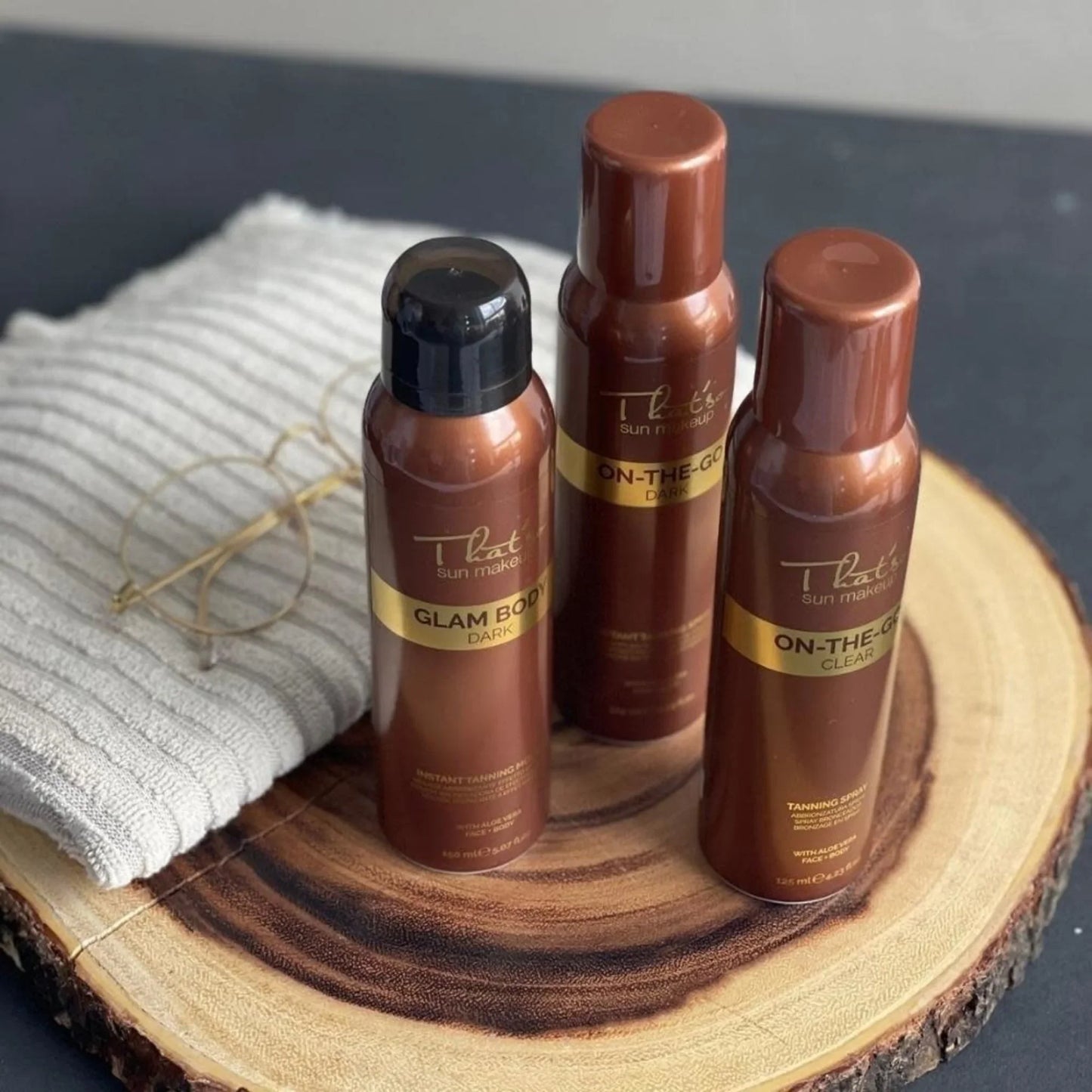 A flat piece of wood holds three bottles of spray on bronzage on the go from That'so.