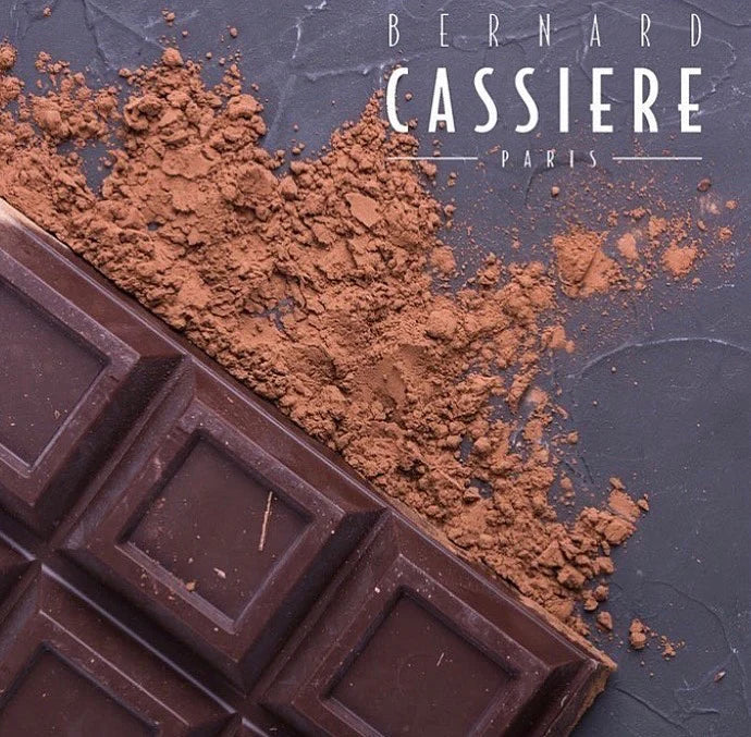 Chocolate bar with cocoa powder and 'Bernard Cassiere Paris' branding on a dark background
