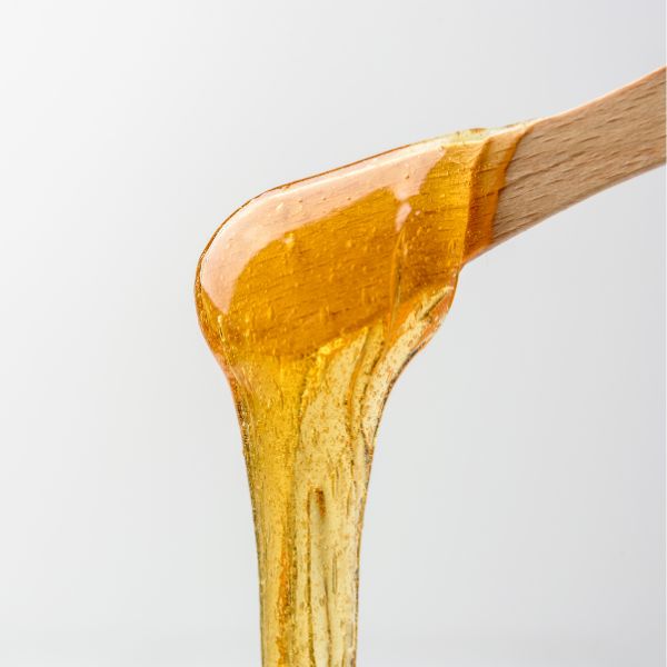 Golden, liquid wax falling off a wooden stick, close up.