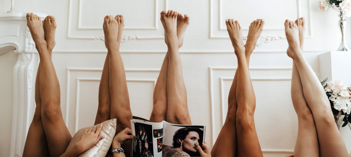 A group of women lay down with their silky smooth legs up in the air.