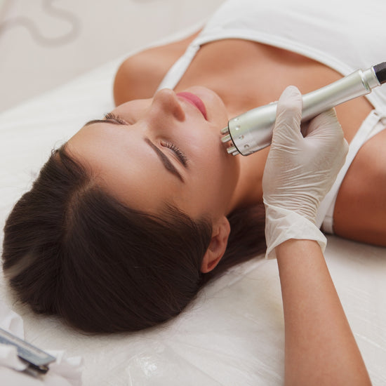 An esthetician uses a device as she conducts a facial treatment on her client.