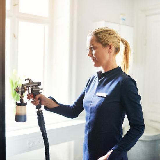 A spray tan technician sprays her client in a tanning studio.