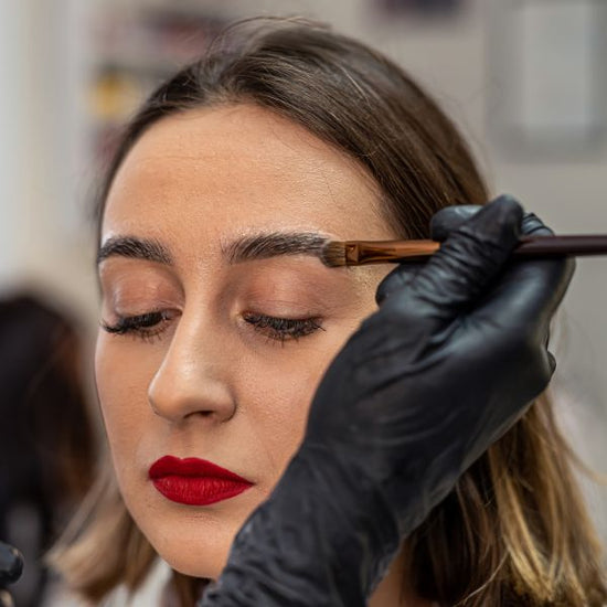 A woman gets eyebrow painting and lamination done in a beauty salon by a certified beauty professional.