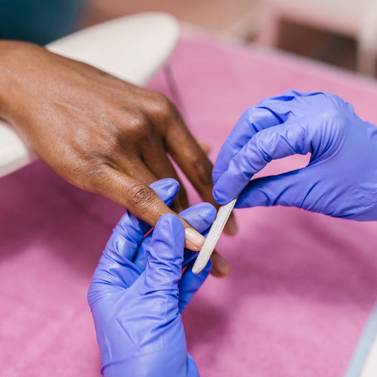 A woman receives a manicure from a beauty professional.