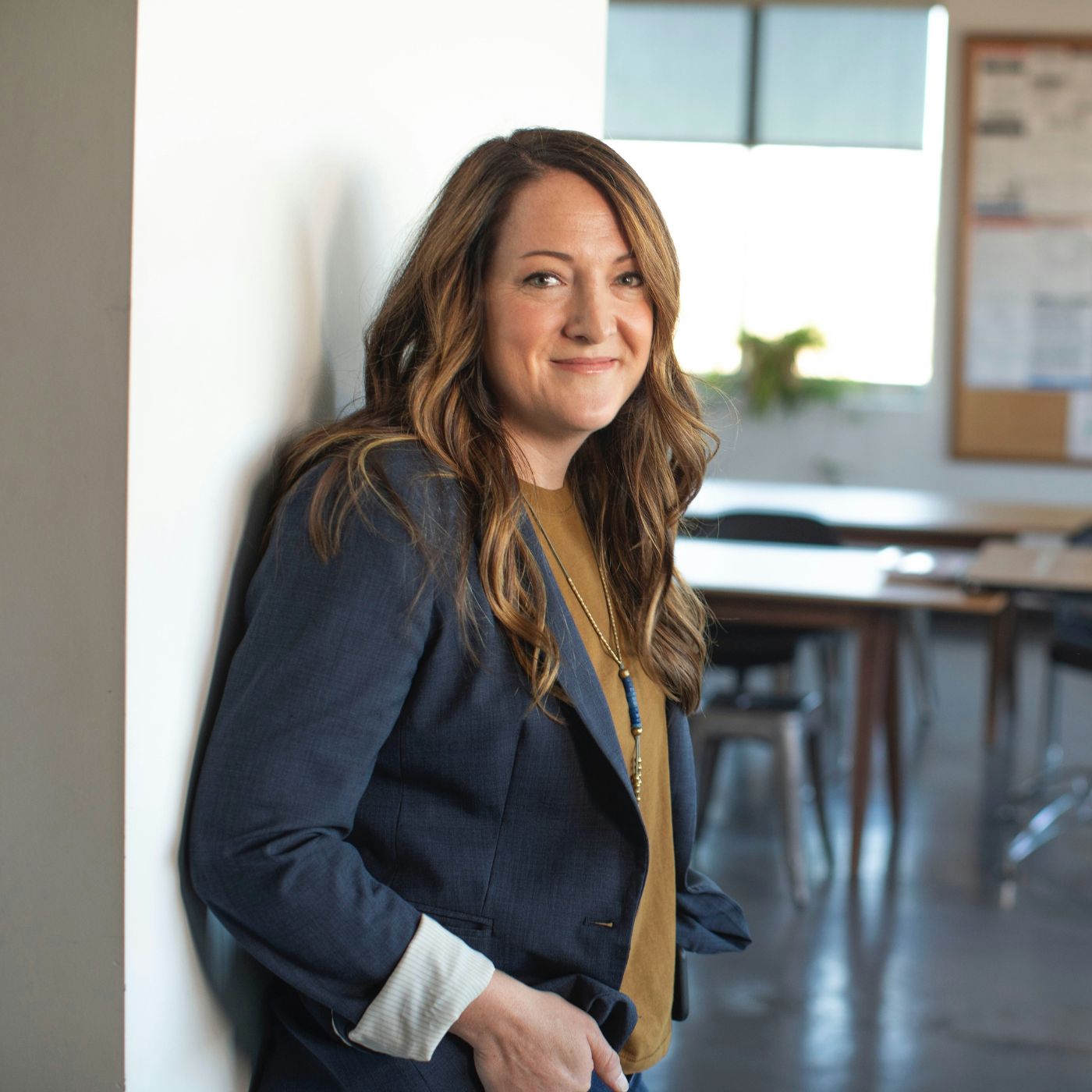 A female business professional leans agains a wall while in her classroom