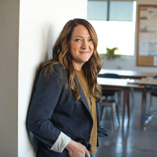 A female business professional leans agains a wall while in her classroom